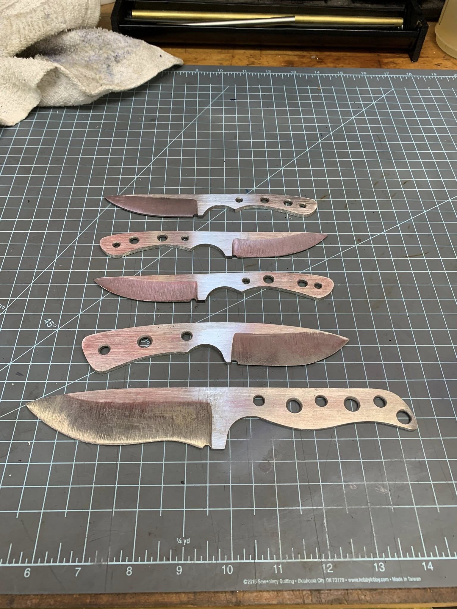 Knife blanks laid out on a shop cutting mat