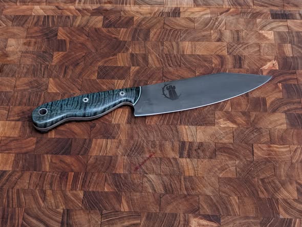 Custom chef knife with blue handle on an end-grain board
